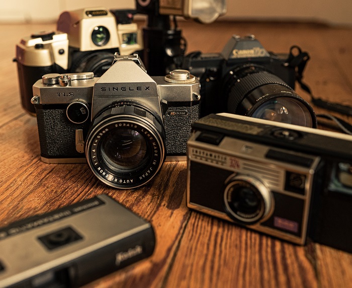 an array of older cameras sat on a wooden table