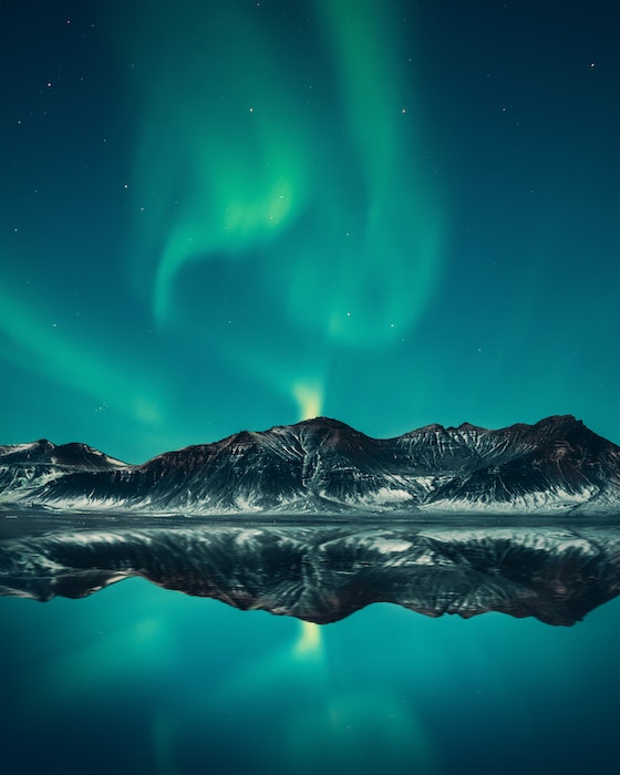 Aurora borealis shot at night with mountains and a reflection in water, shot with one of the best cameras for night photography