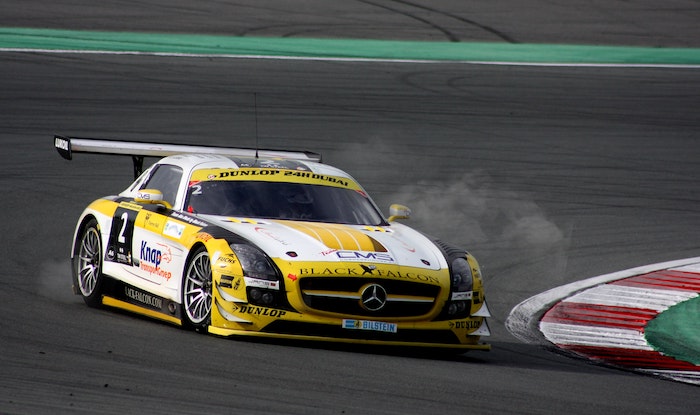 White and yellow racing car speeding around a corner on a race track
