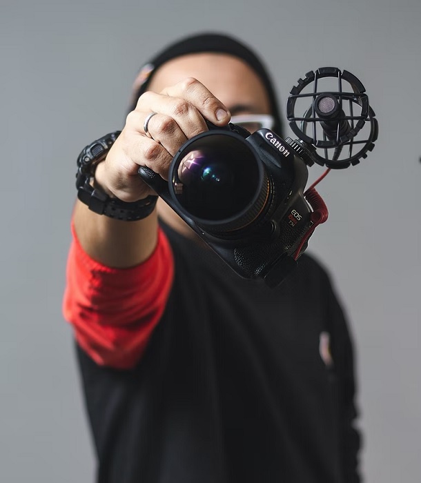 Man holding a canon camera in front of his face