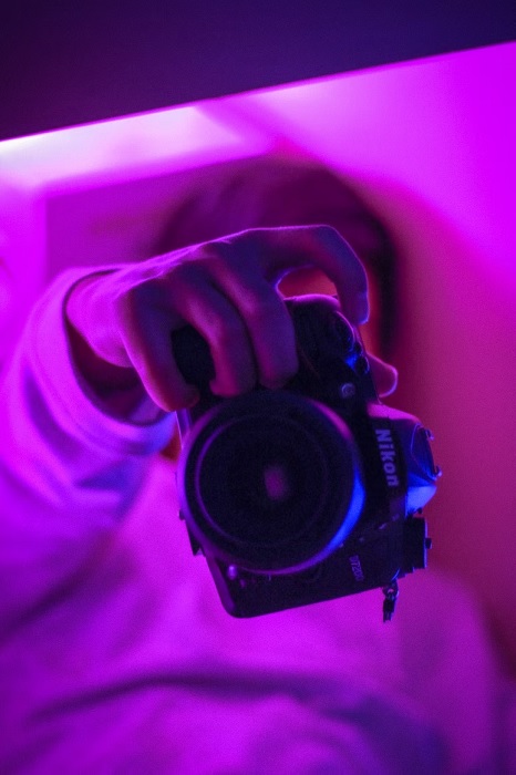 Person holding one of the best Nikon cameras for low light in a room of purple light