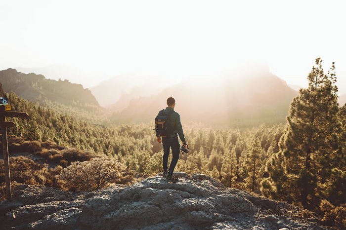 Man with camera standing on a rock looking at a nice view