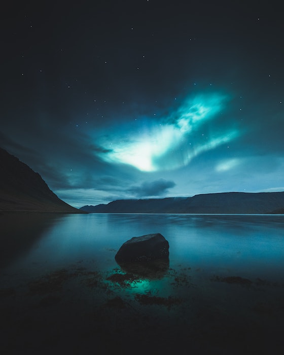 picture of night sky over a body of water with mountains in the distance
