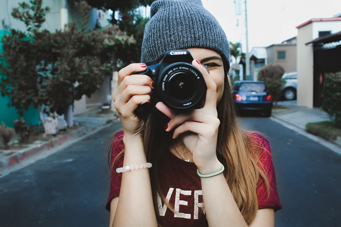 Girl in grey beanie holding canon camera to her face