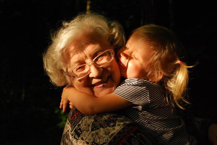 Young girl hugging an old lady with strong directional sunlight