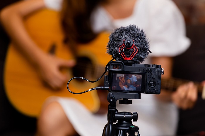 Camera filming a woman playing the guitar