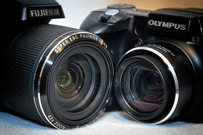 Fuji vs Olympus camera face off with lenses touching