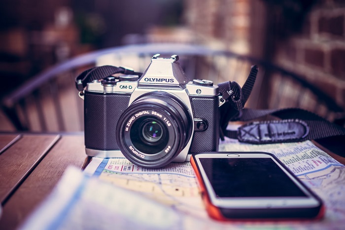 Vintage-looking Olympus Camera on a table with a phone and a map