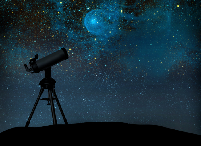 A telescope silhouetted against a starry sky