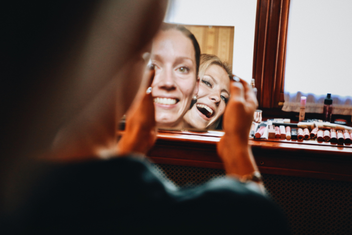 Photo of two women looking at the camera and smiling in a mirror