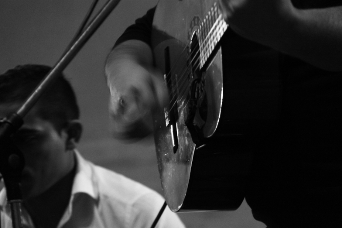 a black and white photo of a hand strumming a guitar