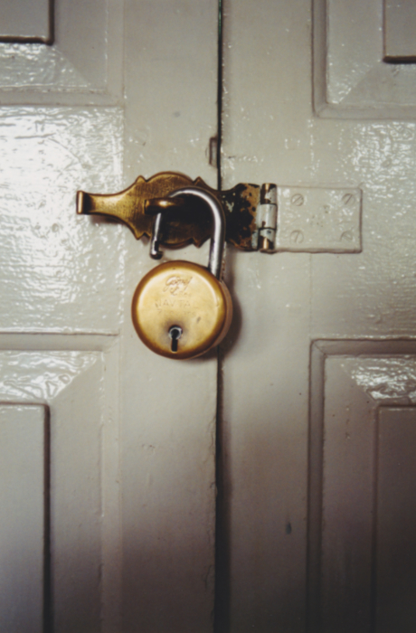 An antique padlock keeping a gray door closed