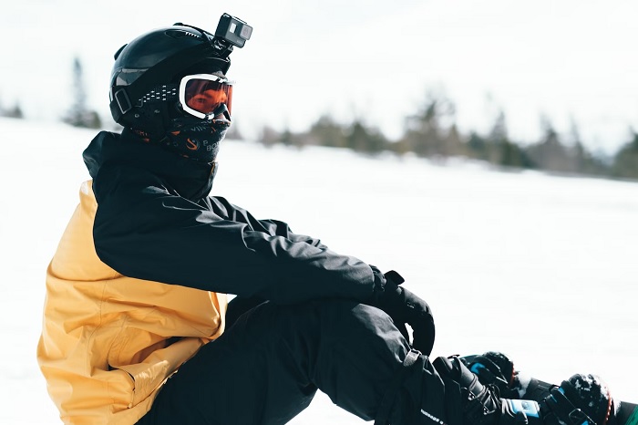 Snowboarder sitting in the snow with an action camera on his helmet