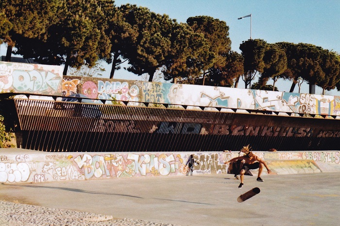 Man with dreadlocks doing a skateboard flip in an urban setting