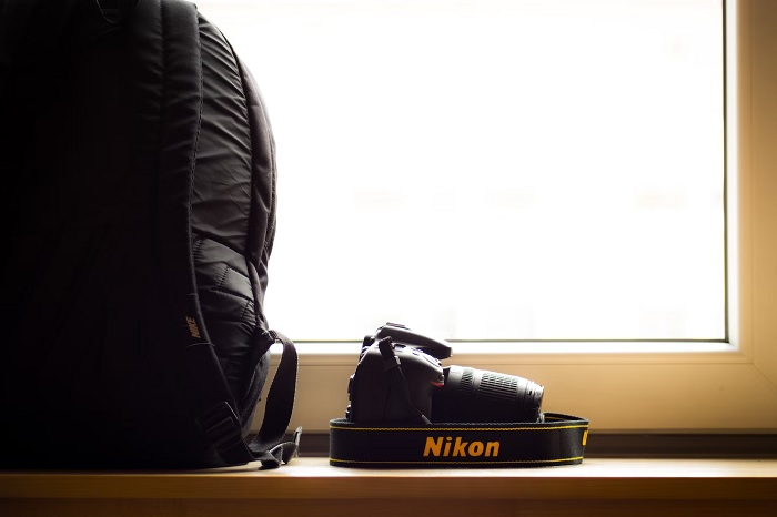 Nikon DSLR next to a backpack on a windowsill 