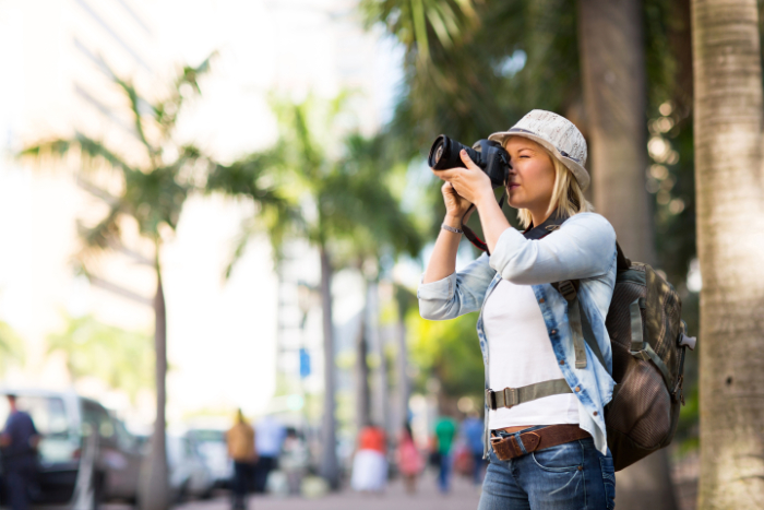 Young woman on holiday, taking a photograph in the street with one of the best cameras for amateur photographers