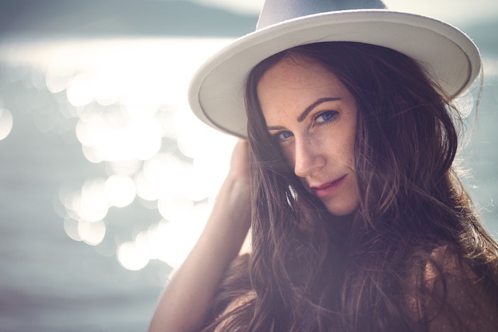 Close-up portrait of a woman with a hat by the water