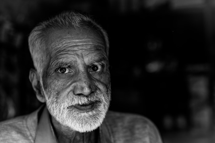 A black-and-white portrait of an older man with a white mustache and beard taken with one of the best Canon portrait cameras