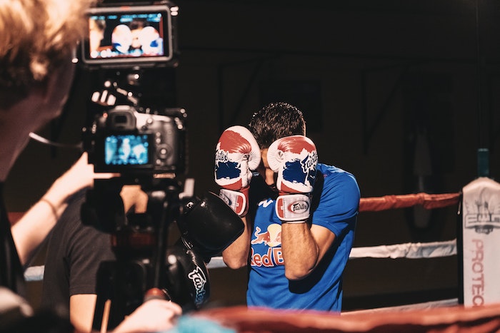 A man filming a boxing match with best Canon 4K DSLR camera on tripod