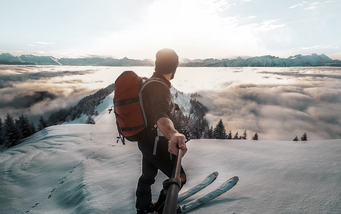 Skier on top of a mountain using an action camera with a selfie stick