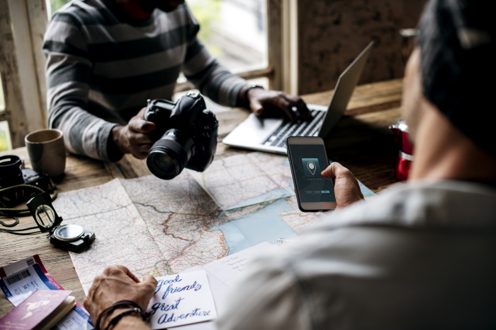 a couple planning a trip with laptop, dslr camera and GPS on phone