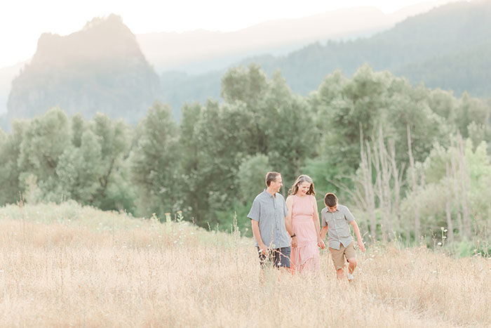 Outdoor family portrait of a family of three walking in a meadow