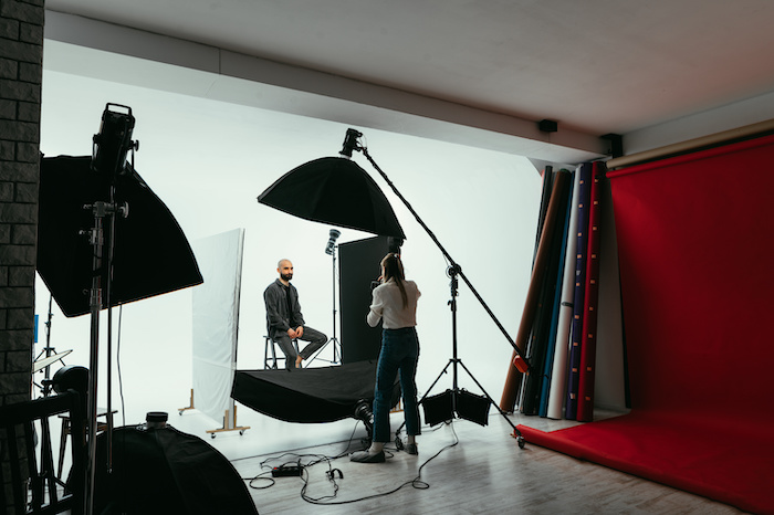 A professional photographer working in a studio with a male model on a white background