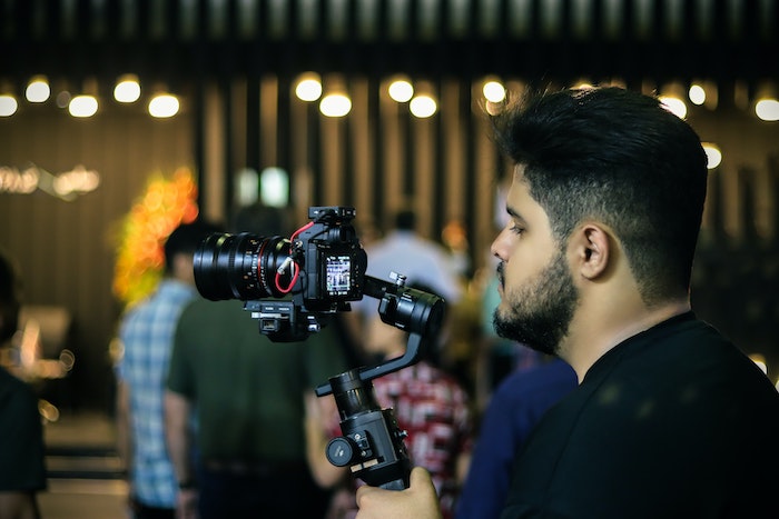 A videographer shooting video with a mirrorless camera, lens, and gimbal