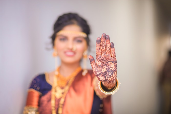 Blurred portrait of a woman with her focused henna hand held up