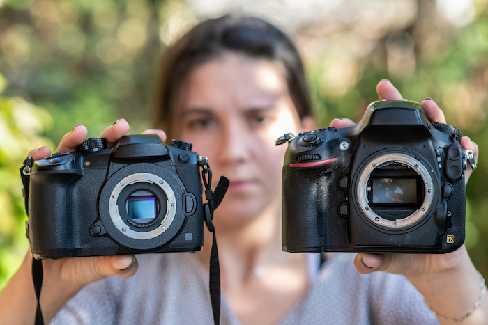 A girl holding mirrorless and DSLR camera with removed lenses and visible matrix