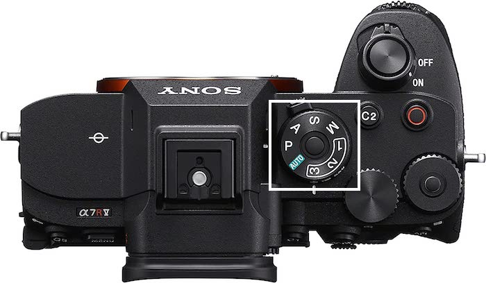 A top view of a Sony a7R V mirrorless camera with it's mode dial button highlighted