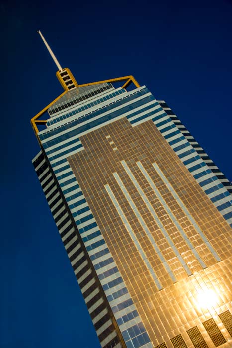 A tilted shot of a Hong Kong skyscraper with gold features against a blue background