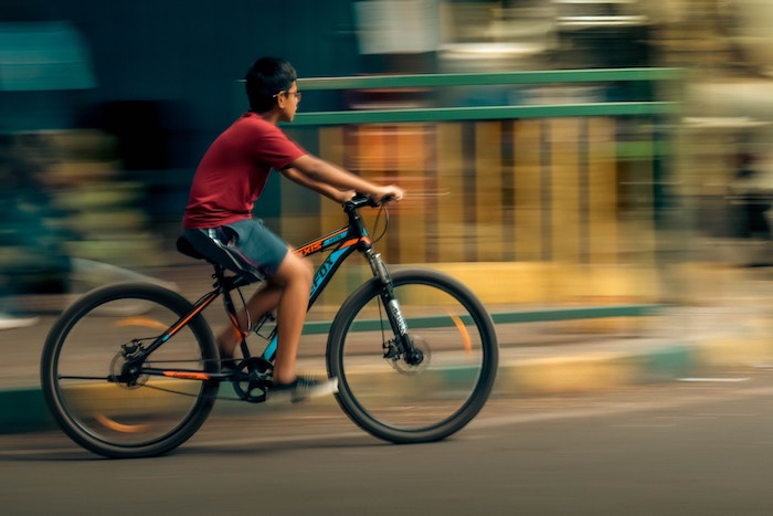 A kid riding a bicycle with the wheels and background blurred