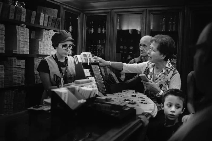 Black-and-white photo of a woman buying something from a cashier in a store with other people