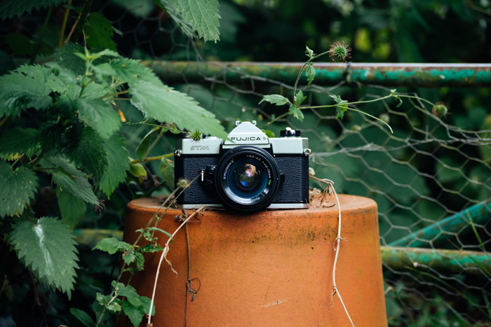  a fujica camera sits on an upside down flower pot outdoors