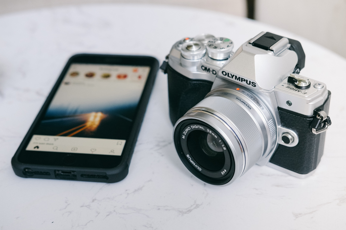 finding camera manuals online: an olympus camera beside a smartphone on a white granite table