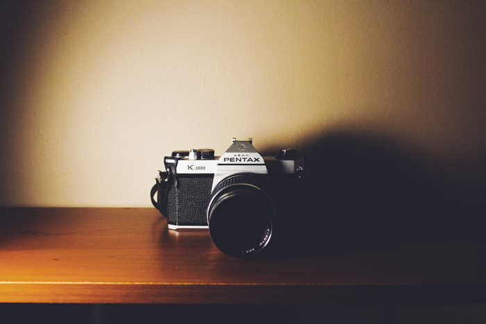  a pentax film camera sitting on a shelf with interesting lighting